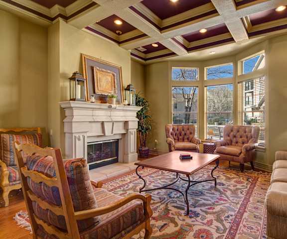 The amazing resident lounge with a fireplace, couches, decorations, large windows with blinds, plush chairs, and coffee tables at Woodland Park Apartment Homes. 