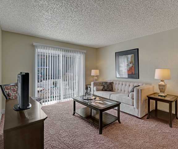 A living room with a couch and a table and sliding glass doors that open onto the patio at Acacia Park. 