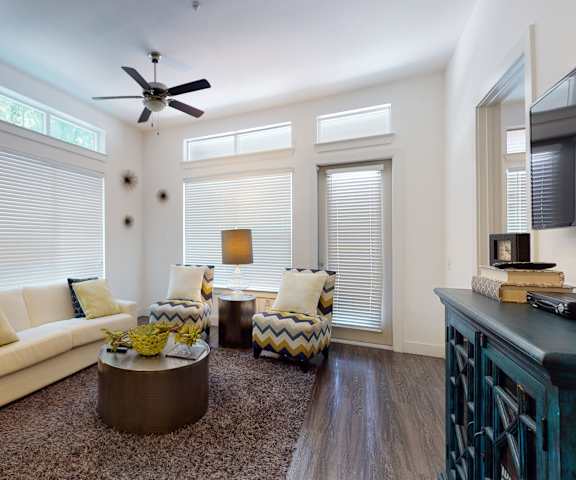 A living room with a couch and chairs and a ceiling fan at Arpeggio. 