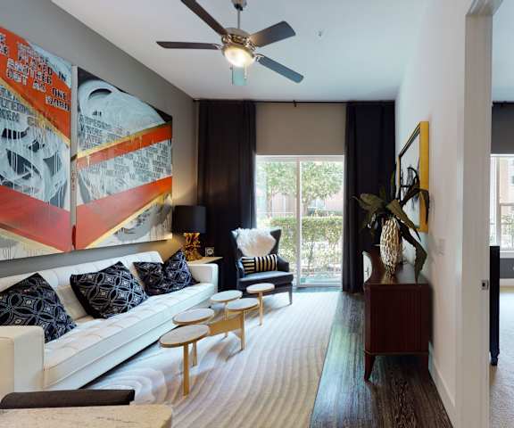 A living room with a couch and a ceiling fan at Arpeggio Apartments. 
