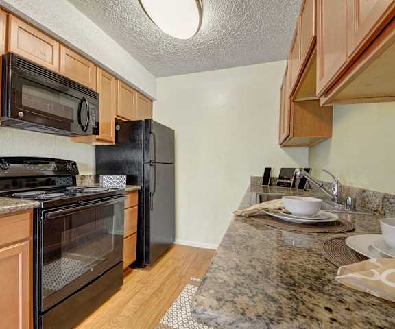 Kitchen with light cabinets, granite countertops, and black appliances at Avalon Springs. 