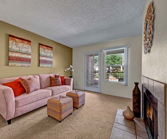 The living room with a couch, coffee table, decorations, a TV, and balcony at Cypress Pointe Apartments. 