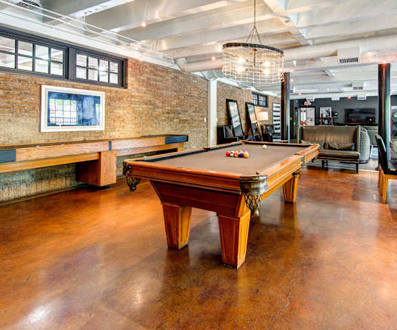 A resident lounge with tables, chairs, and a pool table at Firestone at West 7th. 