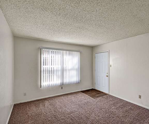 An empty living room with carpeting and the front door at Golden Crest. 
