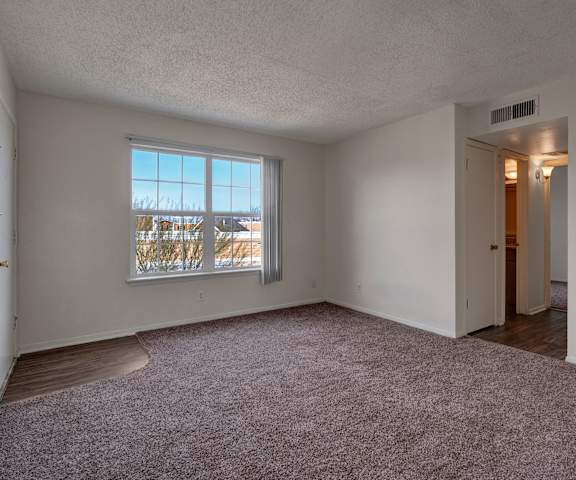 An empty living room with carpeting and the front door at Golden Crest. 