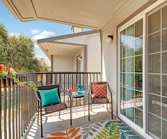 A balcony with a colorful table and chairs at High Plains Apartments. 