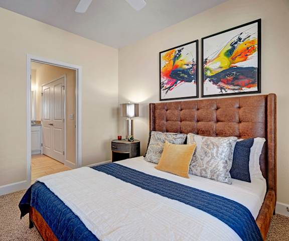 A bedroom with a queen-size bed, a dresser, decorations, window, and nightstands at Latitude 31 Apartments. 
