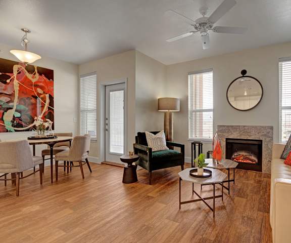 The living room with a couch, plush chairs, coffee table, decorations, a TV, and view of the dining room with a dining table 