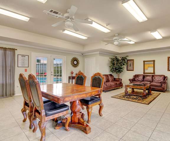 The resident lounge with leather couches, decorations, plush chairs, coffee tables, and French doors to the pool area at Lexington Court Apartment Homes. 