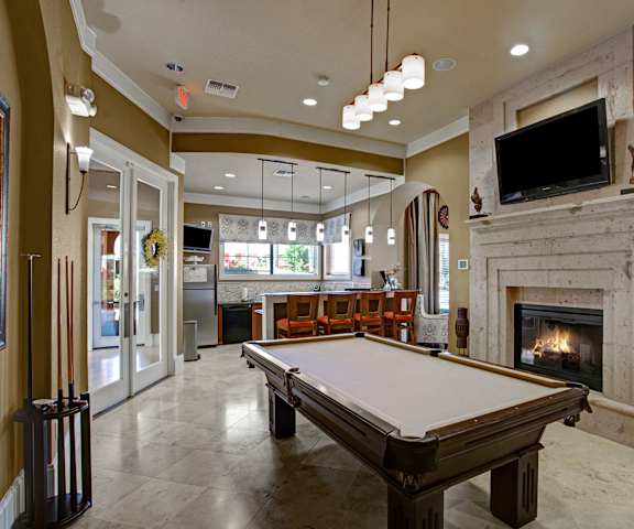 A wonderful resident lounge with tables, chairs, a community kitchen, a fireplace, a TV, and a pool table at the Palms at Briarwood Apartment Homes. 