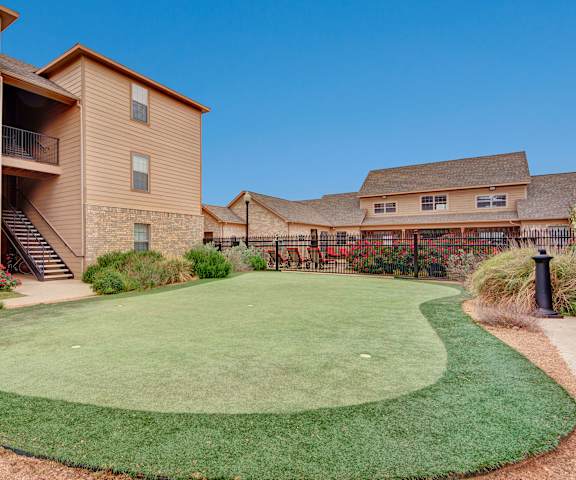 A mini outdoor golf course next to the tan apartment buildings at the Reserve at Abilene Apartment Homes. 