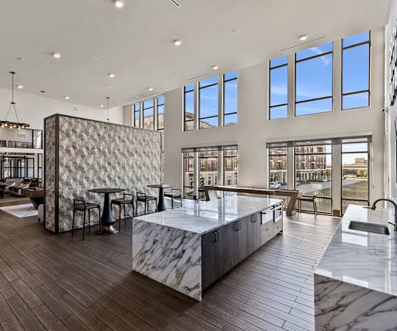 The amazing resident lounge with large windows overlooking the outside, couches, decorations, large windows, a kitchenette, with curtains, plush chairs, and coffee tables at Waterford Apartment Homes. 