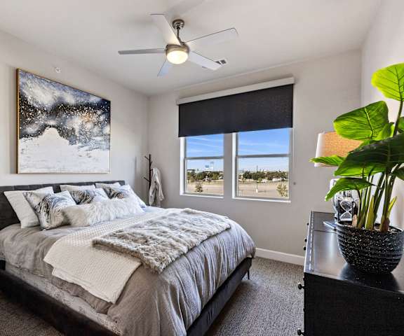 A bedroom with a queen-sized bed and a painting of a snowy landscape on the wall at Waterford Market Apartment Homes. 