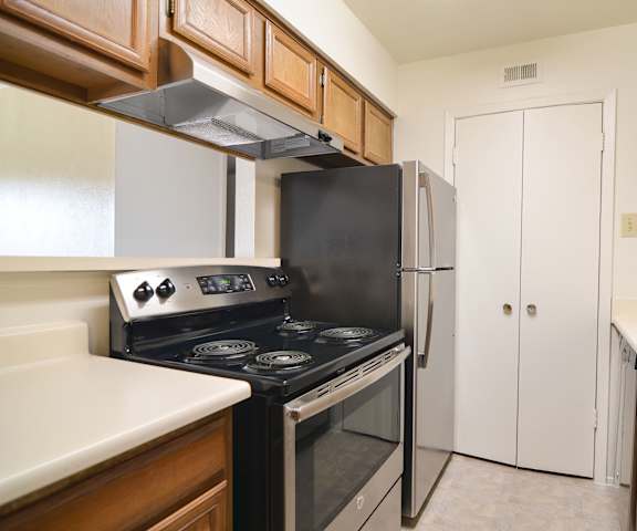 A large/cozy kitchen with stainless steel appliances, light countertops, and large wooden cabinets at Wildflower Apartment Homes. 