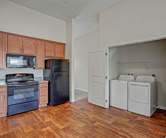 A kitchen with a washer and dryer and a refrigerator and a door open at 600 Riverside