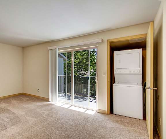 An empty living room with a laundry room and a door to a balcony at Asbury Park. 