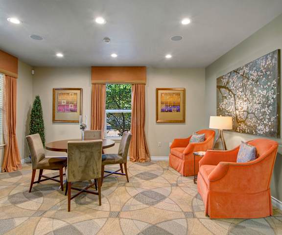 A resident lounge with plush orange chairs and a dining table and chairs. 