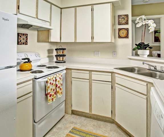 A kitchen with white appliances and counters at Breckenridge Apartments. 