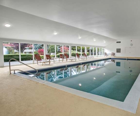 The indoor pool with tables and chairs at Colonial Square Apartments.