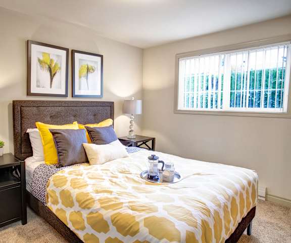 A bedroom with a queen-size bed, closet, and nightstands at Colonial Square Apartments. 
