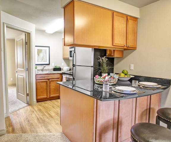 A kitchen with stainless steel appliances and wooden cabinets at Colonial Square Apartments. 