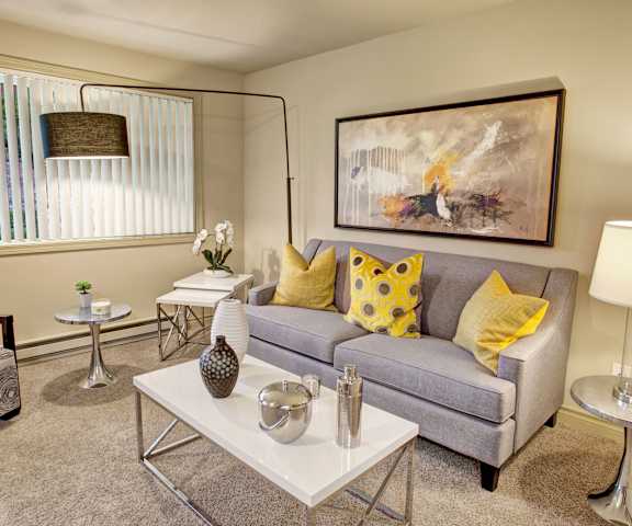The living room with a couch, coffee table, decorations, a TV, and balcony at Colonial Square. 