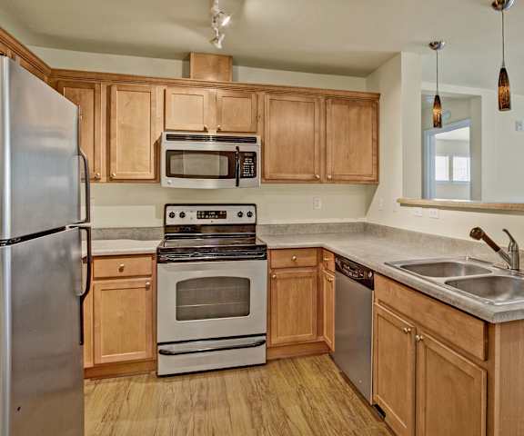 A kitchen with stainless steel appliances and wooden cabinets at Forest Hills Estates.