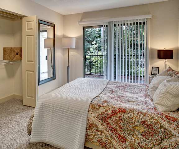 A bedroom with a queen-size bed, a dresser, a balcony, decorations, closet, and nightstands at Heritage Hills. 