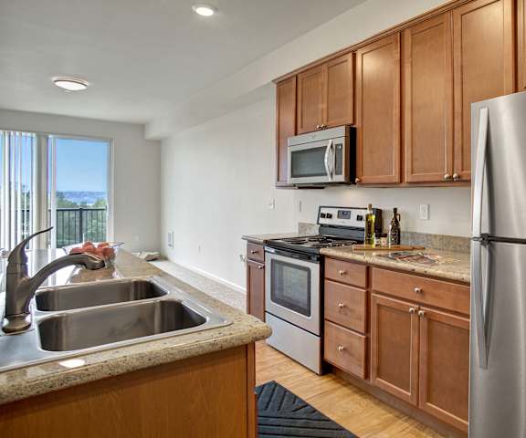A kitchen with stainless steel appliances, marble countertops, and large wooden cabinets at Heritage Hills.