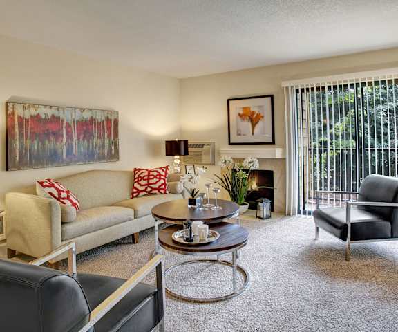 The living room with a couch, plush chairs, coffee table, decorations, a TV, and balcony at Heritage Hills. 