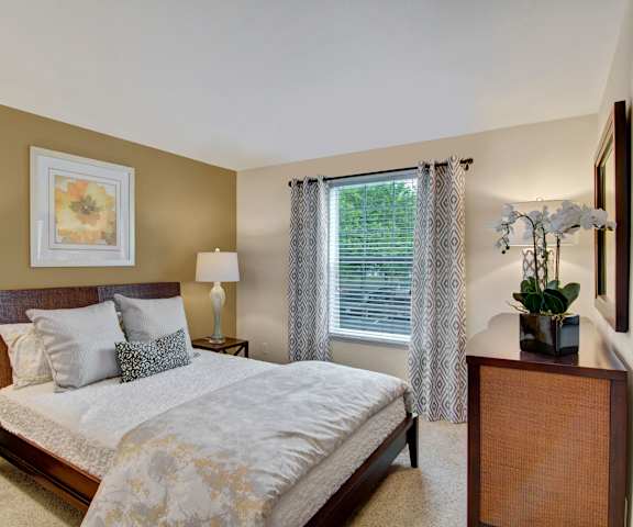 A bedroom with a queen-size bed, dresser, decorations, window, and nightstands at Island Park. 