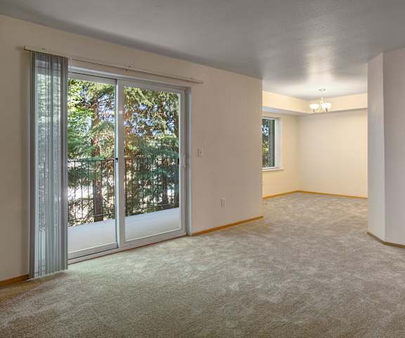 An empty living room with carpeting, a closet, and a door to the balcony at Lake Park Apartments. 