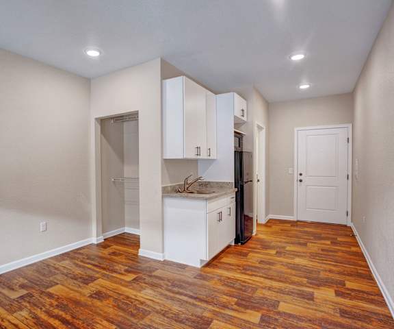 An empty studio apartment with hardwood floors, a closet, and a kitchen at Leavenworth Haus. 
