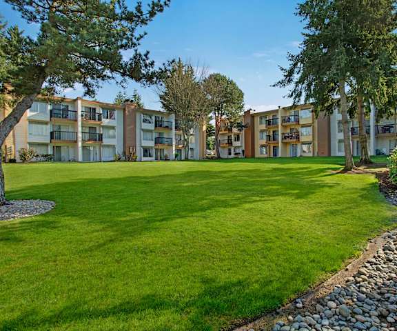 The large, grassy area with a pathway and trees behind the apartment buildings at Soundview Apartment Homes.