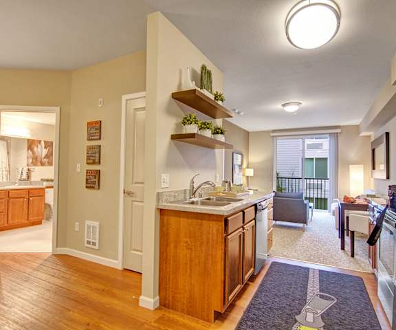 The apartment with a view of the hallway, clean bathroom, beautiful kitchen with stainless steel appliances, and living room with a couch and a balcony at the Artiste Apartment Homes. 