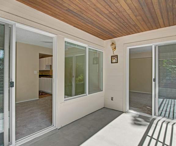 The concrete balcony looking in on the empty carpeted apartment from two sliding glass doors at Watercrest Apartment Homes. 
