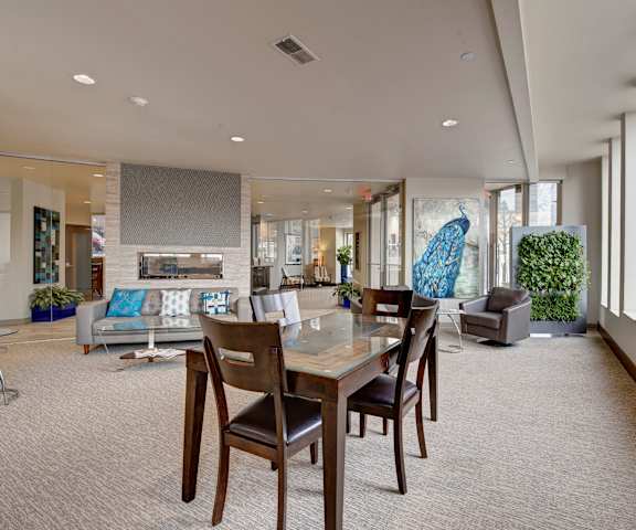 The resident lounge with couches, coffee tables, and a dining table and chairs at Avenir Apartments. 