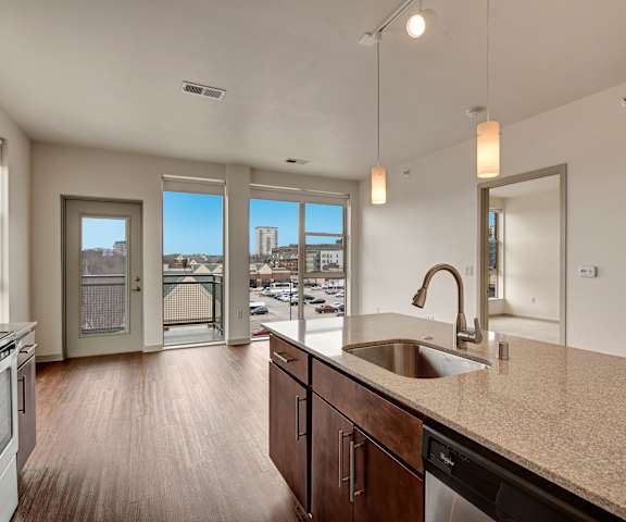 An open kitchen and living room with a view of the city and a balcony at Avenir Apartments. 