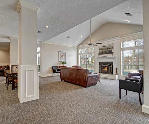 The large, well lit, amazing resident lounge with couches, decorations, large windows, a fireplace, unique overhead lighting, plush chairs, and coffee tables at St. James Place Apartment Homes. 