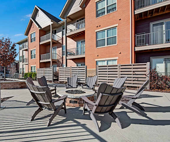 Seven black chairs surrounding a firepit with brick buildings in the background at the Vue at Pinnacle Peak Apartment Homes. 