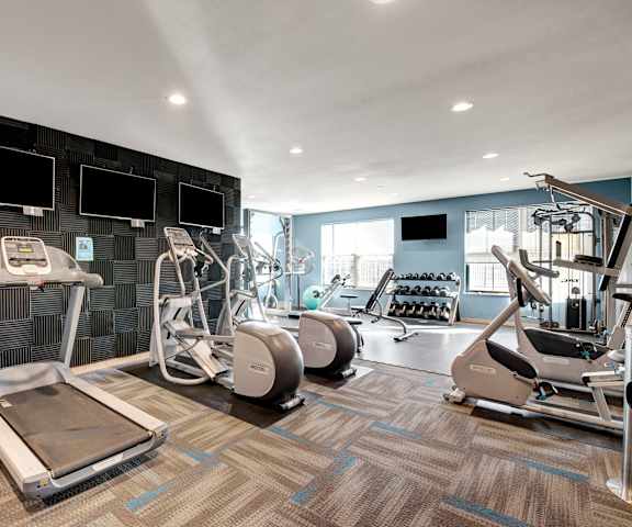 A spacious gym with TVs, weights, treadmills, elliptical machines, and other exercise equipment at the View at Pinnacle Peak Apartment homes. 