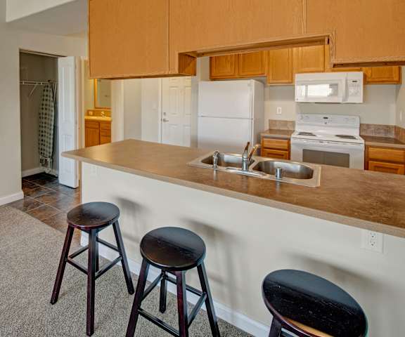 A kitchen with white appliances and counters at Confluence at Harvest Hills. 