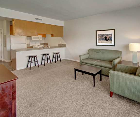 The living room with a couch, coffee table, decorations, a TV, and a view on the kitchen at Confluence at Harvest Hills. 