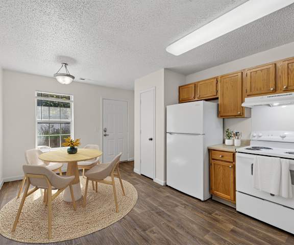 A kitchen with a white fridge, oven and dining table with chairs.