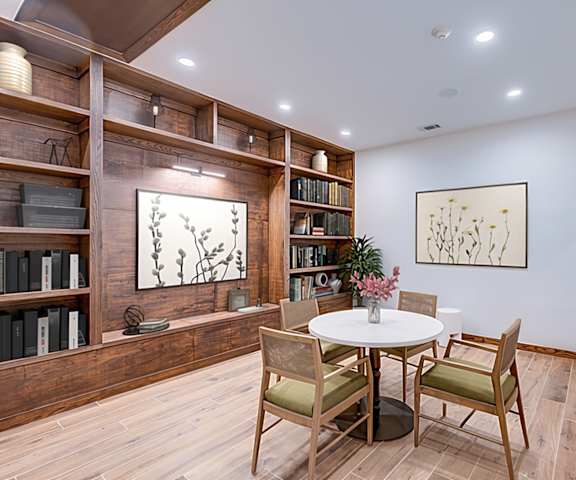 A dining room with a table set for two and a bookshelf filled with books.