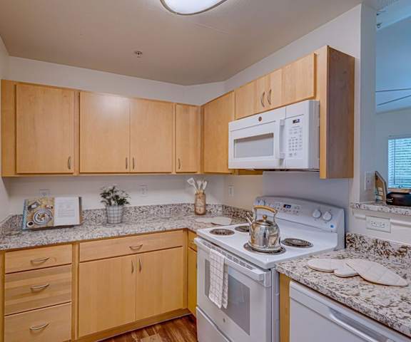 A kitchen with a white microwave above a stove and wooden cabinets.