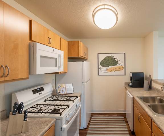 A kitchen with a white stove top oven and a white refrigerator.