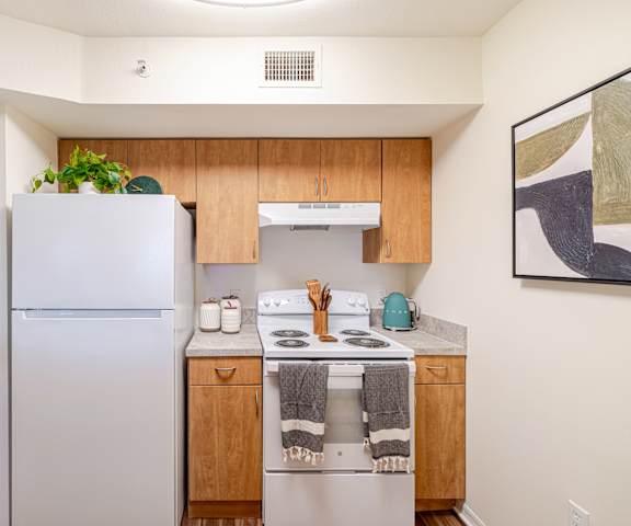 A kitchen with a white refrigerator and wooden cabinets.