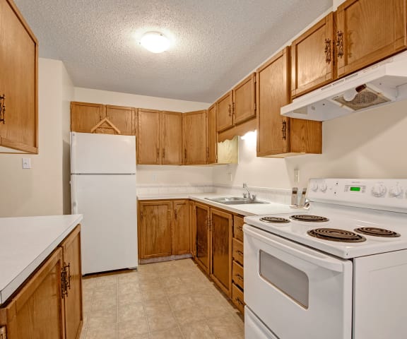 A kitchen with white appliances and counters at Broadmoor Apartments. 