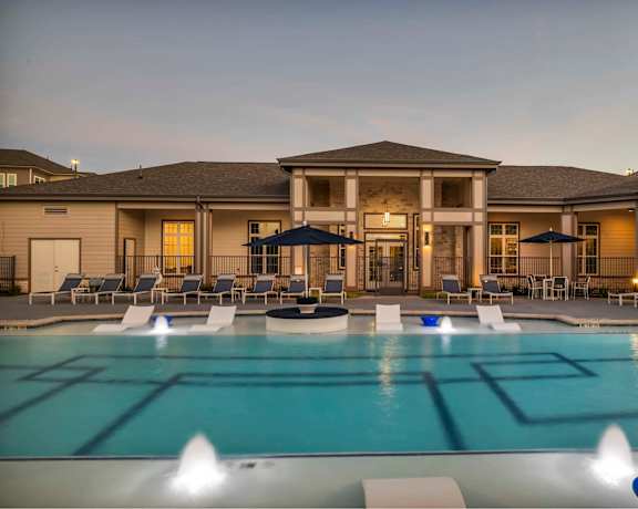 a large pool with chairs and umbrellas at dusk